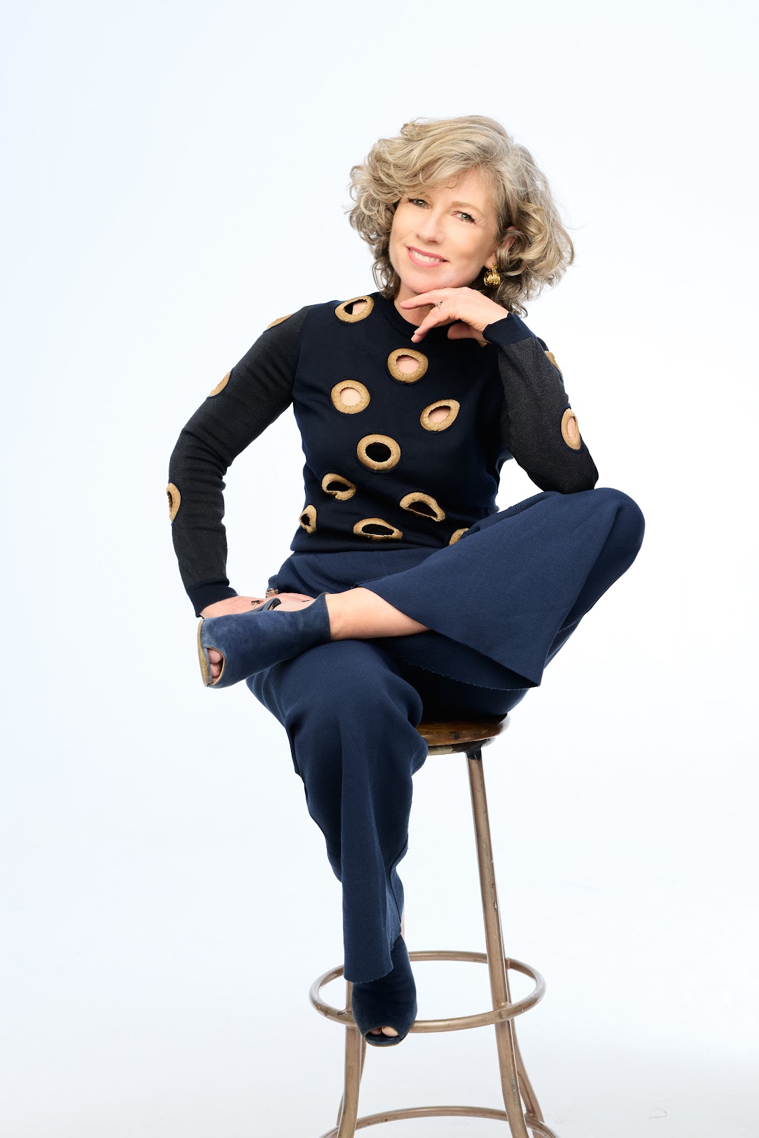 Sonya Lennon seated on a stool, smiling thoughtfully
